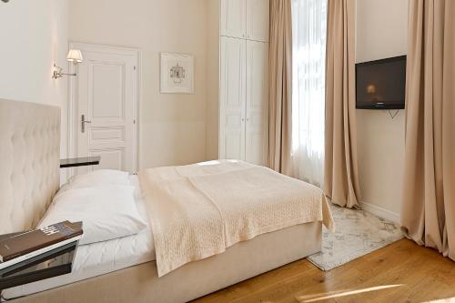 a white bedroom with a bed and a television at 6 rooms in Vienna