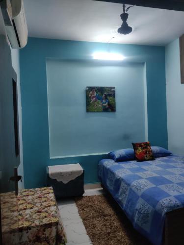 a bedroom with blue walls and a bed and a tv at Mato Shree Aashray in Gaya