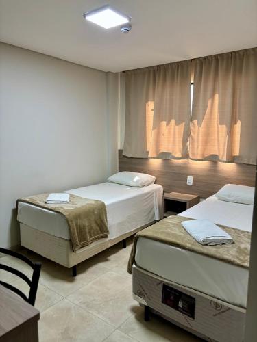 a hotel room with two beds and a window at Hotel Accordes in Campo Grande