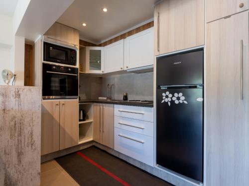 Una cocina con refrigerador negro y gabinetes de madera. en Apartment Arcona by Interhome, en Bredene