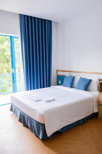 a bedroom with a large bed with blue curtains at Turi Staypoint in Quang Ngai