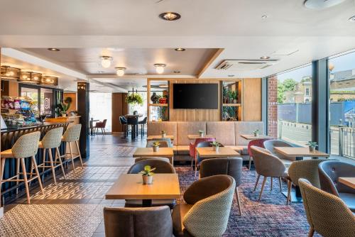 a restaurant with tables and chairs and a bar at Point A Hotel London Canary Wharf in London