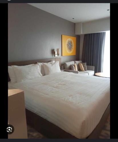 a bedroom with a large white bed and a couch at Novotel Hotel Residences Manila by AMORE Suites in Manila