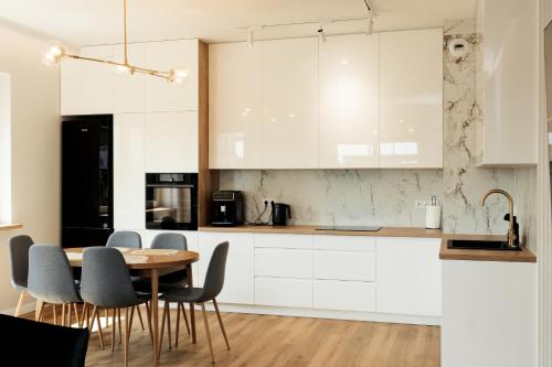 une cuisine avec des armoires blanches et une table et des chaises dans l'établissement Apartament Komfort, à Uniejów
