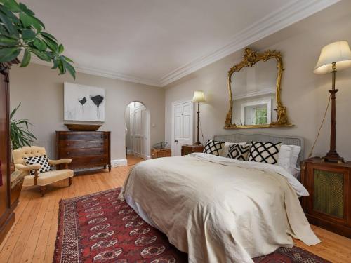 a bedroom with a large bed and a mirror at Holiday Home Glenquiech House by Interhome in Angus