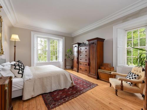 a bedroom with a bed and a chair and windows at Holiday Home Glenquiech House by Interhome in Angus