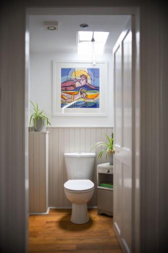 a bathroom with a toilet and a painting on the wall at Holiday Home Glenquiech House by Interhome in Angus