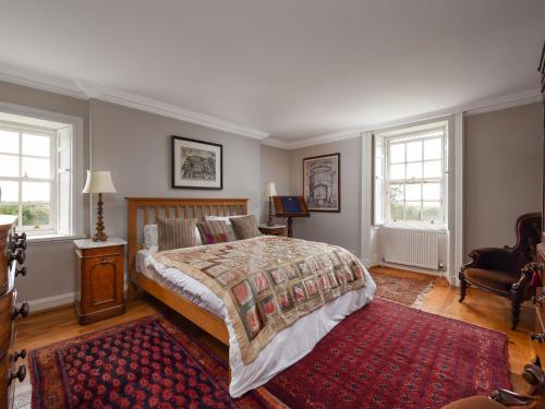 a bedroom with a large bed and a red rug at Holiday Home Glenquiech House by Interhome in Angus