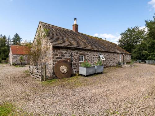an old stone house with two plants in front of it at Holiday Home Glenquiech House by Interhome in Angus