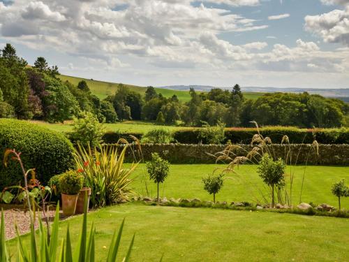 a garden with green grass and bushes and trees at Holiday Home Glenquiech House by Interhome in Angus