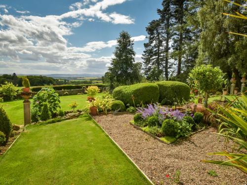 a garden with green grass and flowers and bushes at Holiday Home Glenquiech House by Interhome in Angus