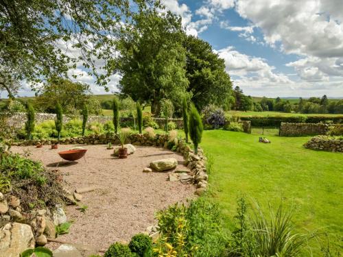 a garden with a gravel patio and a tree at Holiday Home Glenquiech House by Interhome in Angus