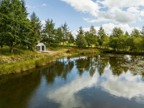 a river with a white building in the distance at Holiday Home Glenquiech House by Interhome in Angus
