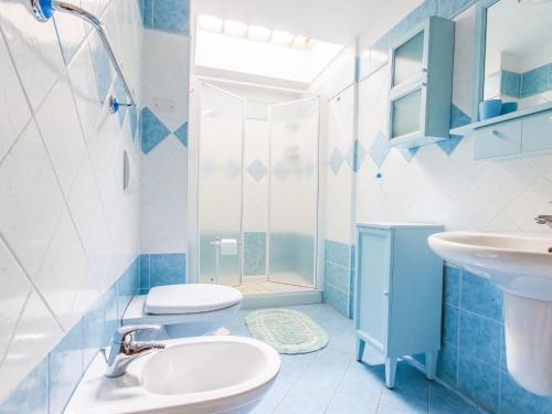 a blue and white bathroom with a sink and a toilet at Chalet Baita al Compo by Interhome in Borgo