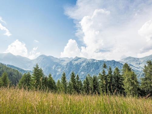 a row of trees in a field with mountains in the background at Chalet Baita al Compo by Interhome in Borgo