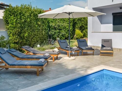 a group of chairs and an umbrella next to a pool at Holiday Home Gabi by Interhome in Brtonigla