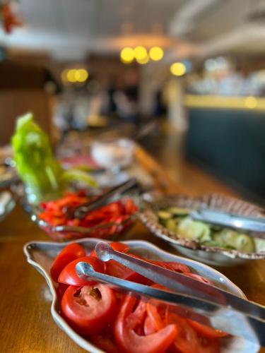 a table topped with plates of tomatoes and tongs at Akademihotellet in Uppsala
