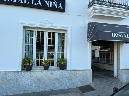 a white building with potted plants in a window at Hostal Restaurante La Niña in Palos de la Frontera