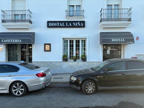 two cars parked in front of a building at Hostal Restaurante La Niña in Palos de la Frontera