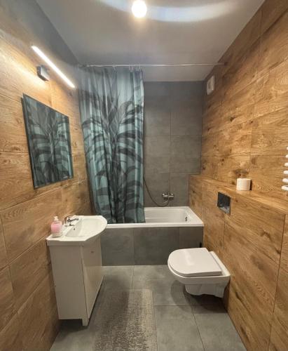 a bathroom with a toilet and a sink and a bath tub at Holdek Apartamenty Ceglana in Katowice