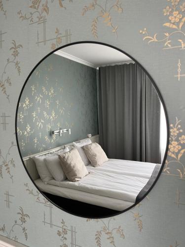 a mirror in a bedroom with a bed in it at Akademihotellet in Uppsala