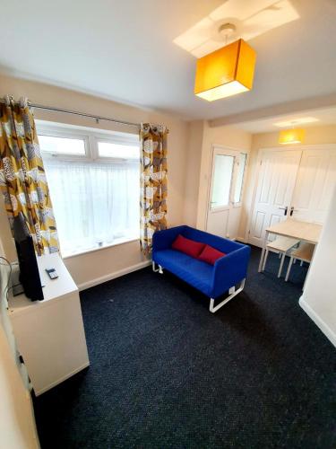 een woonkamer met een blauwe bank en een raam bij 4 Bedroom Rayleigh Town House in Rayleigh