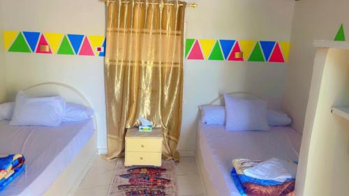 two twin beds in a room with a curtain at Wateen guest house in Jazīrat Aswān