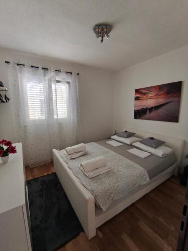 a white bedroom with a bed and a window at Anja in Vir
