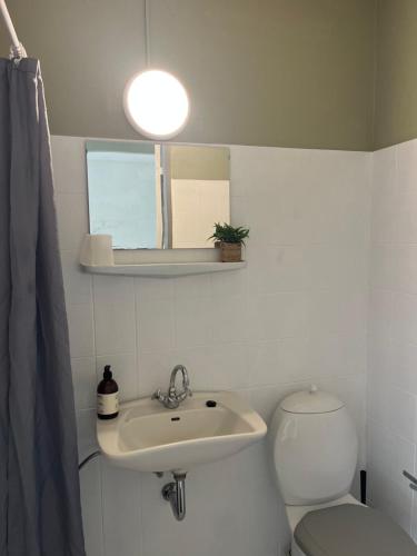 a bathroom with a sink and a toilet and a light at Døstrup Landevejskro & Motel in Skærbæk