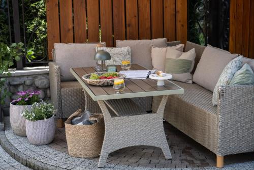 a patio with a couch and a table and chairs at Willa Podhalanka Jacuzzi & sauna - drewniany dom dla 20 osób in Biały Dunajec