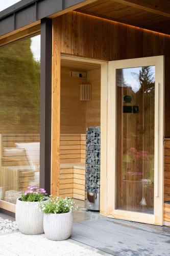 a building with two flower pots in front of a door at Willa Podhalanka Jacuzzi & sauna - drewniany dom dla 20 osób in Biały Dunajec