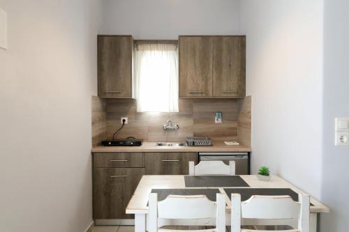 a kitchen with wooden cabinets and a table and chairs at Niriides rooms in Kionia