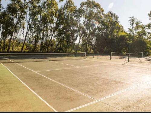 un campo da tennis con rete e alberi sullo sfondo di Le Papyrus -T2 Domaine Pierres et Vacances "Les Restanques du golf de Saint Tropez" à Grimaud a Grimaud