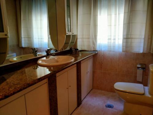 ein Badezimmer mit Waschbecken, Toilette und Spiegel in der Unterkunft Chalet con piscina in Tabagón