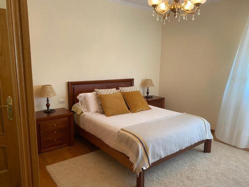 Schlafzimmer mit einem Bett mit Kissen und einem Kronleuchter in der Unterkunft Chalet con piscina in Tabagón