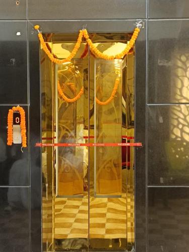Un ascensor de cristal con cortinas naranjas en una pared. en Hotel Shree Radhe & Banquet, en Darbhanga