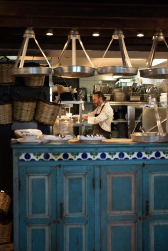 a man standing behind a blue counter in a kitchen at Phāea Blue - Small Luxury Hotels of the World in Elounda