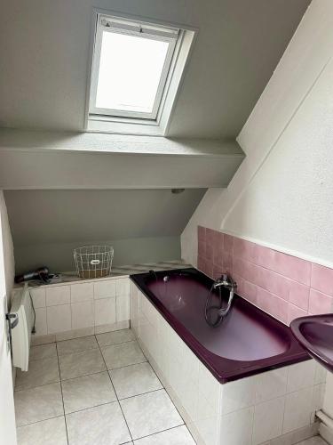 a bathroom with a purple bath tub and a window at Le secret d'Opale in Wissant