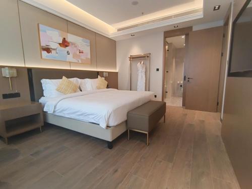 a bedroom with a large white bed and a bathroom at Golden Tulip Kin-Oasis Kinshasa in Kinshasa