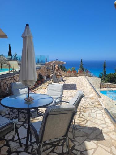 a patio with a table and chairs and the ocean at Villa ioli breathtaking view & sunset in Agios Nikitas