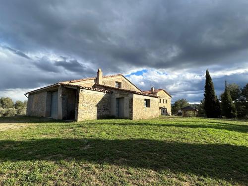 an old house in a field with a cloudy sky at Casa Rural Mas María in Horta de San Joan