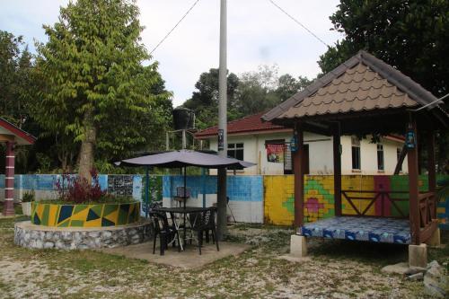 a house with a table and an umbrella in the yard at Capital O 91187 D'dusun Raudhah Chalet in Baling
