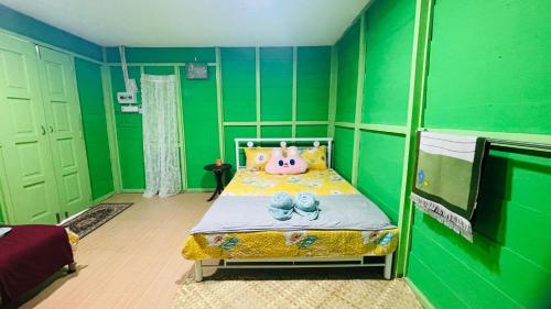 a small green room with a bed with shoes on it at Capital O 91187 D'dusun Raudhah Chalet in Baling