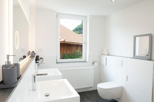 a white bathroom with a toilet and a window at Dorfwirt Pfronten in Pfronten