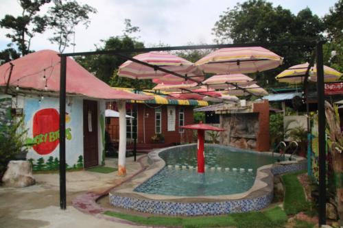 a pool with umbrellas in front of a house at Capital O 91187 D'dusun Raudhah Chalet in Baling