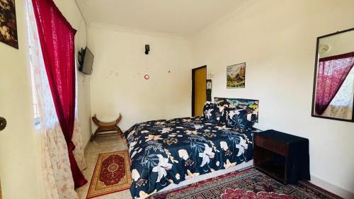 a bedroom with a bed with a blue comforter at Capital O 91186 Rumah Rehat Bukit Inas 