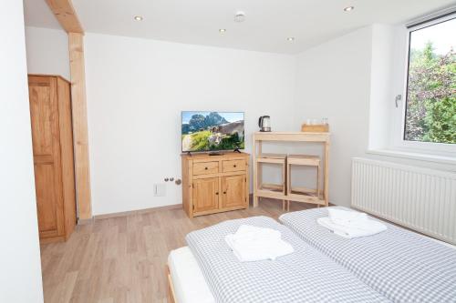 a white room with two beds and a kitchen at Dorfwirt Pfronten in Pfronten
