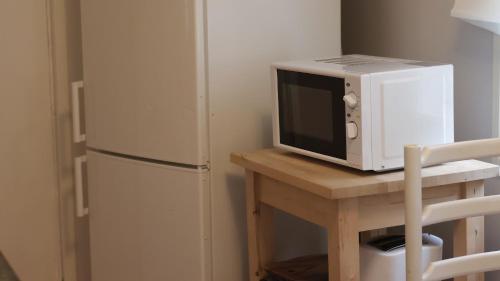 a microwave sitting on a table next to a refrigerator at Kodit Tuulikinkatu in Mikkeli