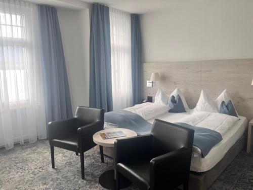 a hotel room with a bed and two chairs at Hotel Restaurant Bellevue au Lac in Thun