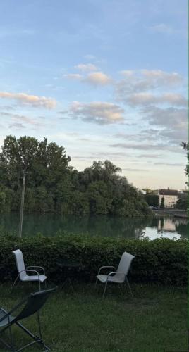 two chairs sitting in the grass next to a lake at Merlin Cottage in Montereau-Fault-Yonne